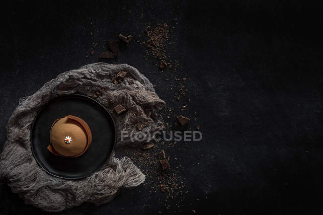 Schokoladenkuchen garniert mit Gänseblümchen auf dunklem Hintergrund — Stockfoto