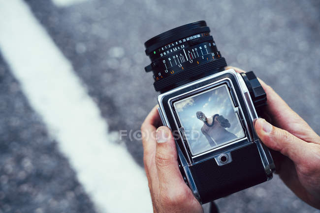 Mãos humanas segurando câmera com vista de homem nu com máscara de gás lacrimogêneo na estrada — Fotografia de Stock