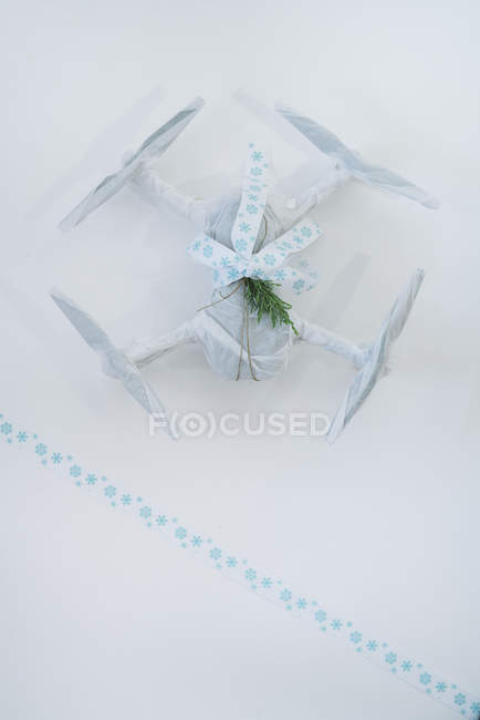 Drohne verpackt als Weihnachtsgeschenk mit elegantem blau-weißen Band und Tannenzweig auf weißem Hintergrund — Stockfoto