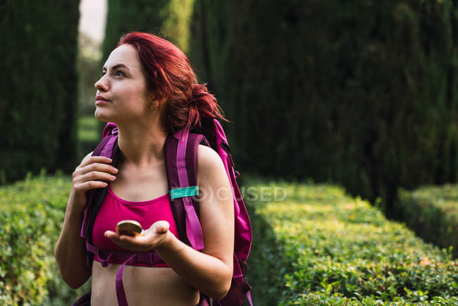 Жінка з рюкзаком і компасом в руці ходить в парку — стокове фото