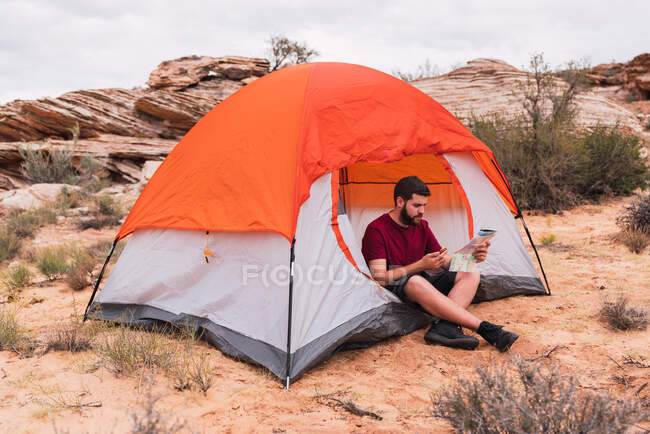 Traveler using map and compass at tent — Stock Photo