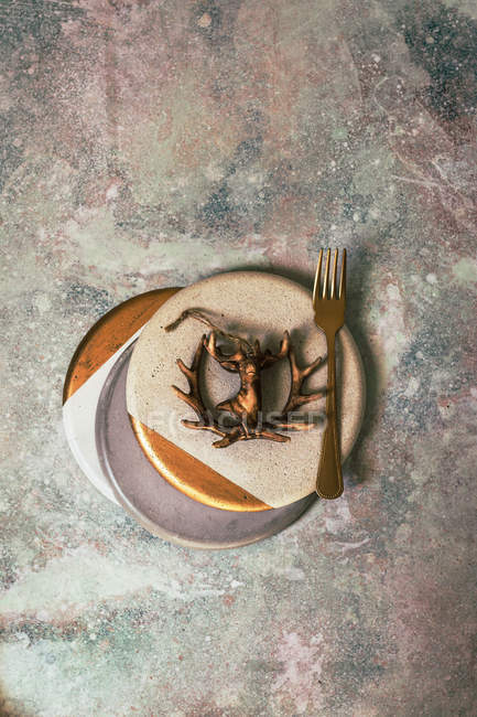 Christmas table set in white and gold colors decorated with figure of deer on concrete surface — Stock Photo