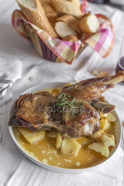 Agnello arrosto con patate servito su piatto su tovaglia bianca — Foto stock