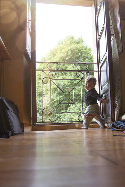 Младенец с любопытством смотрит в дверь — стоковое фото
