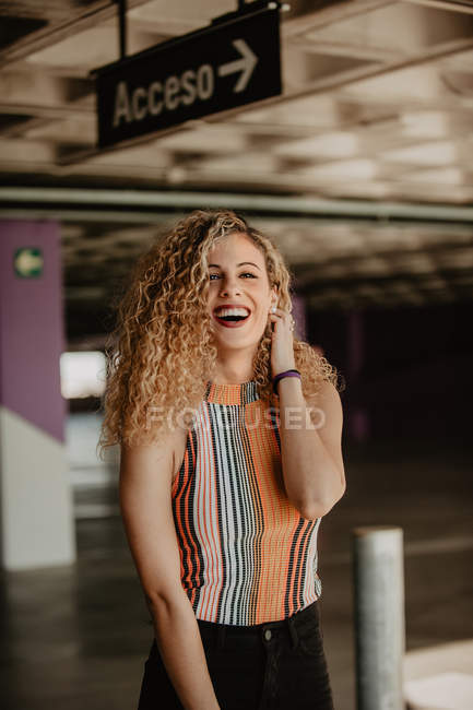 Портрет улыбающейся кудрявой блондинки с яркими губами в полосатой блузке — стоковое фото