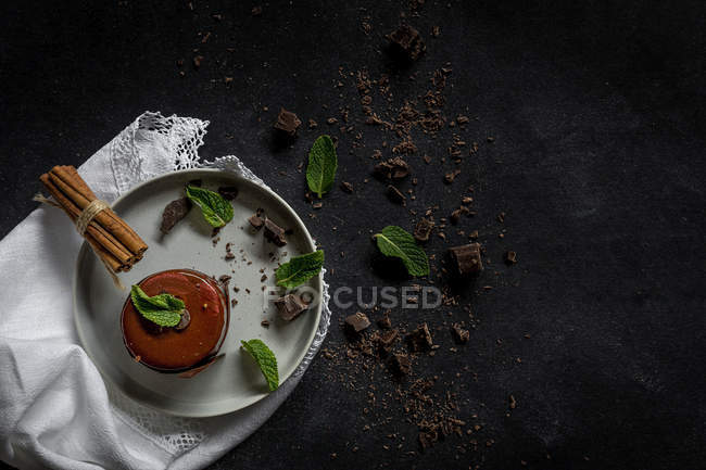Pastel de chocolate con menta, trozos de chocolate y canela sobre fondo negro - foto de stock