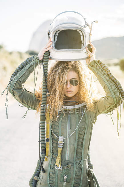 Уверенная женщина в костюме космонавта надевает шлем на солнце — стоковое фото