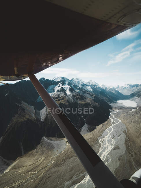 View of snowy mountains under plane wing — Stock Photo