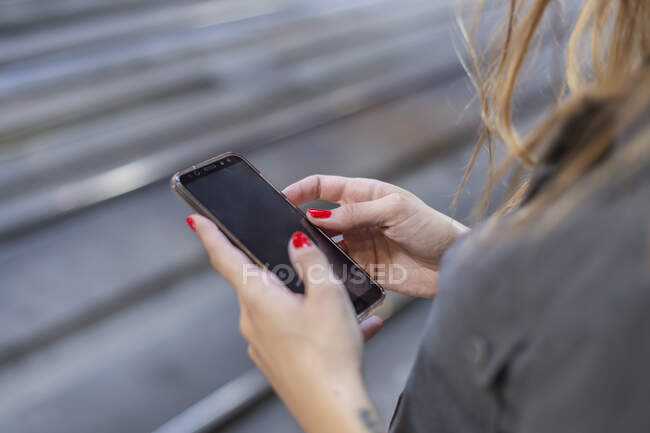 Woman using smartphone on railway station — Stock Photo