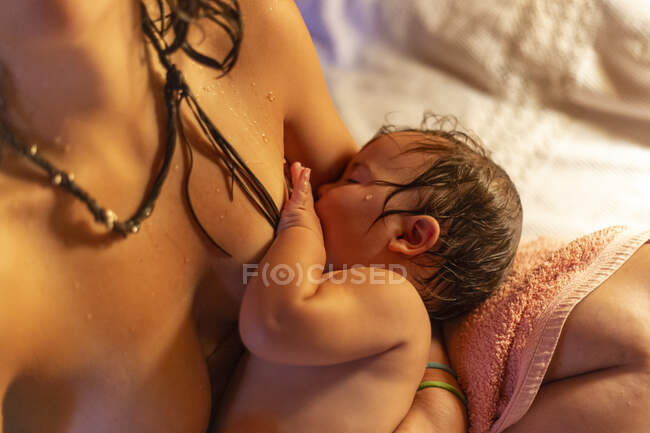 Tiro de colheita de cima da mulher molhada sentada com o bebê a mãos e amamentação — Fotografia de Stock