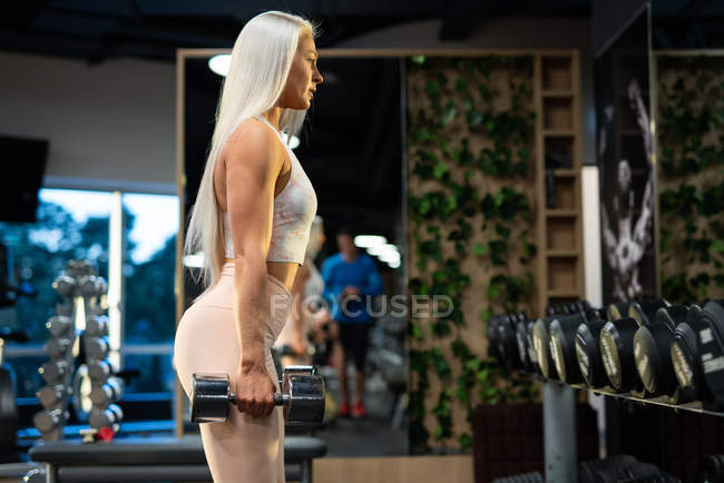 Sportlerin turnt im Fitnessstudio mit Kurzhanteln — Stockfoto