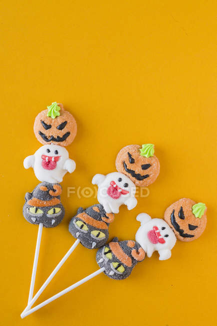Doces de Halloween em paus no fundo laranja — Fotografia de Stock