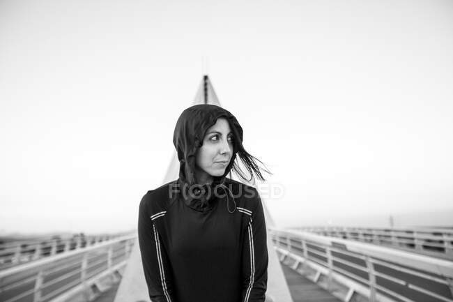 Femme en sportswear noir debout sur la construction moderne du pont regardant confiant — Photo de stock