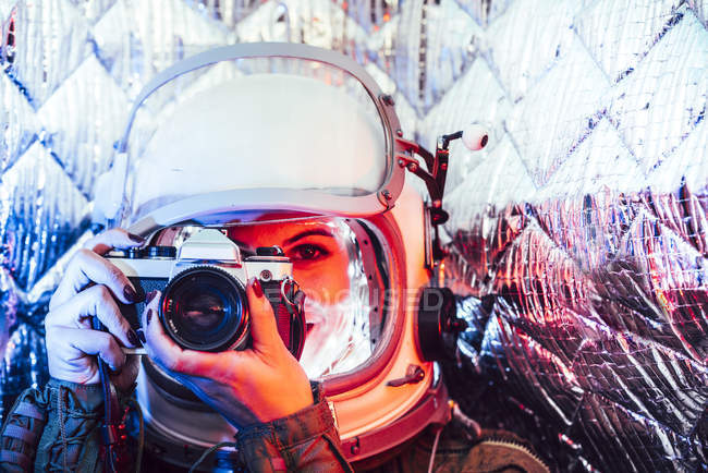Girl wearing old space helmet and costume holding photo camera — Stock Photo