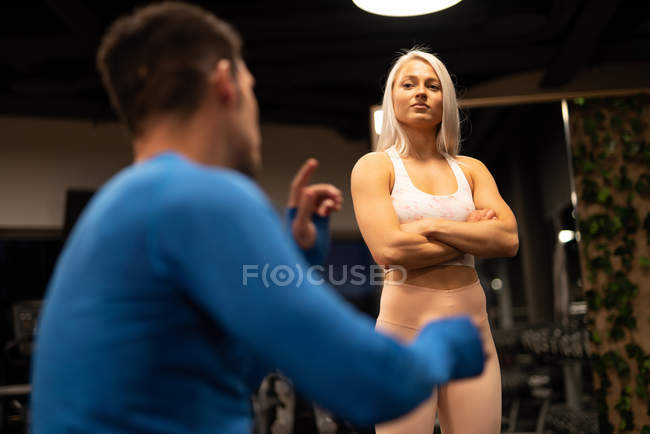 Mujer atlética y hombre hablando en el gimnasio - foto de stock