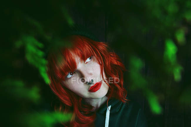 Jeune femme aux cheveux roux entre les rameaux de sapin sur fond noir — Photo de stock