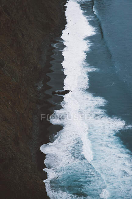 From above shot of magnificent foamy waves of amazing sea rolling near cliff on island of Tenerife, Spain — Stock Photo