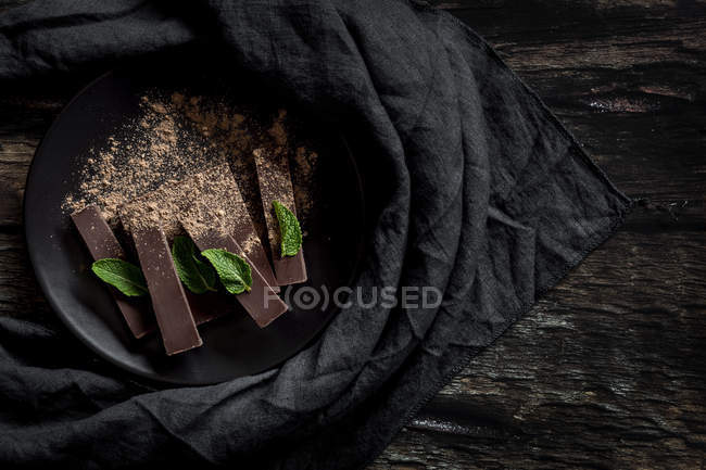 Chocolate pieces and chunks with mint on dark wooden background — Stock Photo