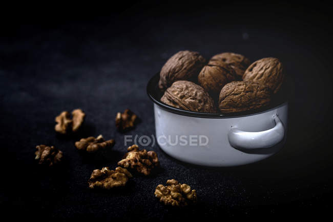 Nueces secas sin cáscara y sin cáscara en bandeja sobre fondo negro - foto de stock