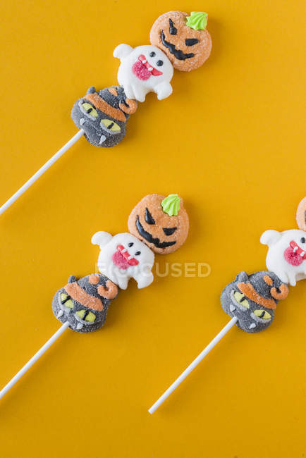 Bonbons d'Halloween sur bâtons sur fond orange — Photo de stock