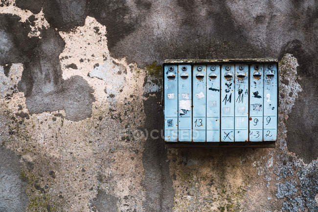 Boîte aux lettres altérée accrochée à un mur de béton en ruine sur la rue de la ville — Photo de stock