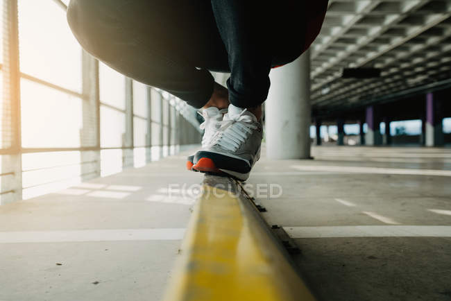 Close-up of male feet in sneakers walking on rail in building — Stock Photo