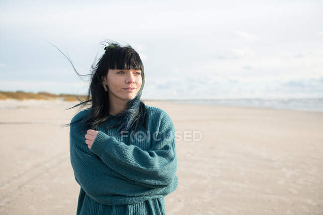 Жінка стоїть на пляжі, дивлячись далеко — стокове фото