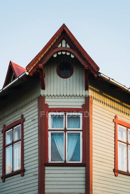 Fenêtres sous le toit ornemental de la vieille maison sur fond de ciel bleu — Photo de stock