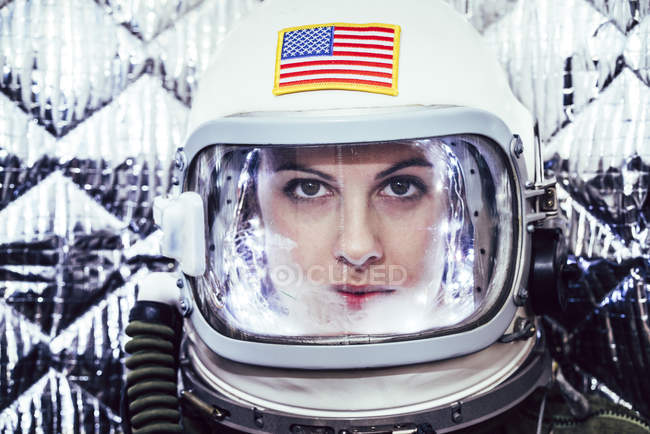 Confident girl wearing old space helmet with american flag sign on foil background — Stock Photo