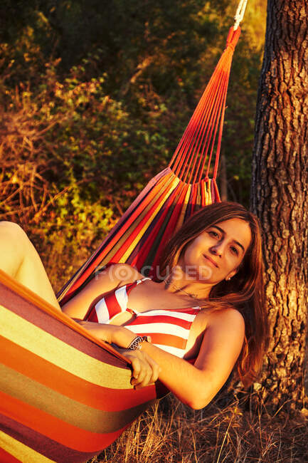 Femme couchée dans un hamac dans des bois ensoleillés — Photo de stock