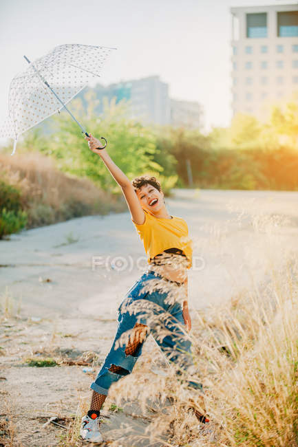 Alegre joven mujer sosteniendo paraguas al aire libre en tiempo soleado - foto de stock