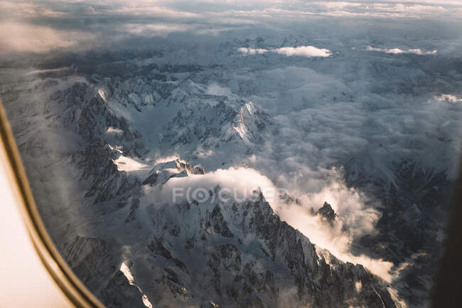 Magnificent view of clouds and snow of beautiful Alps from window of plane — Stock Photo