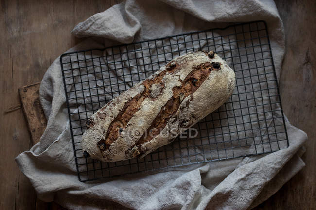Hogaza de delicioso pan de centeno con arándanos y nueces en la rejilla en la mesa de madera - foto de stock