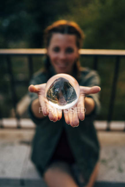Крупним планом руда дівчина тримає кришталевий м'яч з відображенням — стокове фото