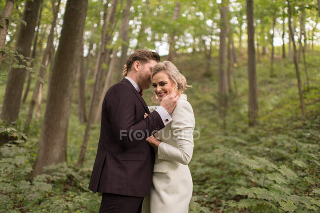 De arriba toma de abrazar a la novia y el novio adultos de pie en los bosques verdes - foto de stock