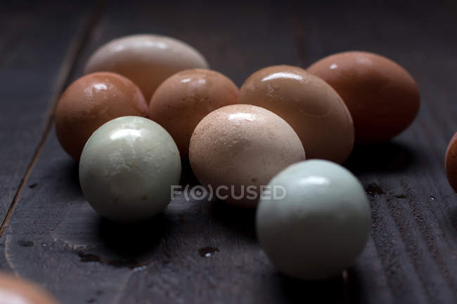 Uova bianche e marroni con guscio bagnato sul tavolo di legno scuro — Foto stock