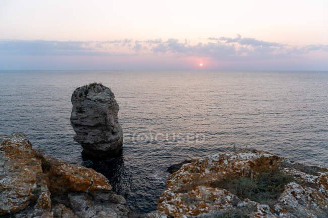 Increíbles rocas gruesas de pie en aguas tranquilas durante el hermoso atardecer en Tyulenovo, Bulgaria - foto de stock