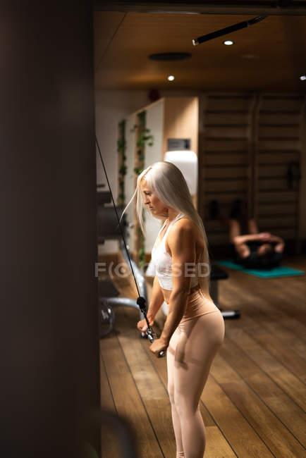 Young blond woman in sportswear doing exercise in gym — Stock Photo