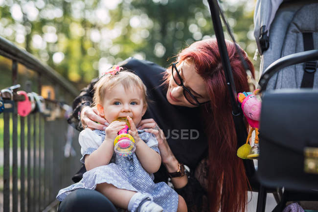 Mãe brincando com bebê menina no parque ensolarado — Fotografia de Stock