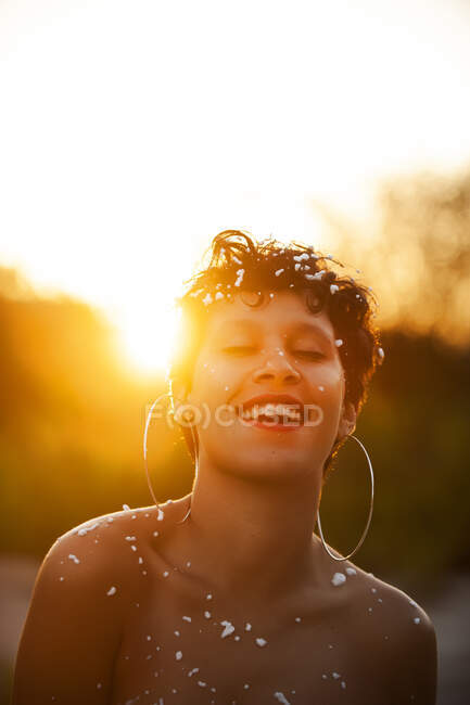 Приваблива молода леді гола і коротке волосся вкрита пінопластами весело сміється, стоячи на вулиці під час заходу сонця — стокове фото