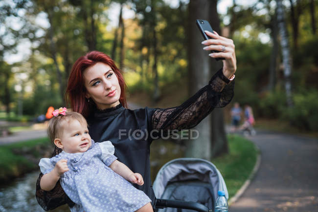 Мати бере селфі з веселою дівчинкою в парку — стокове фото
