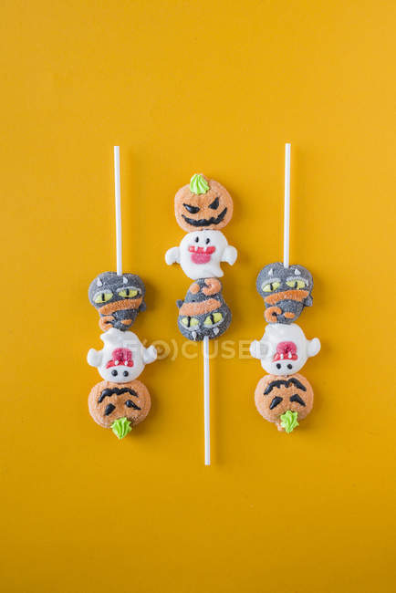 Caramelos de Halloween sobre palos sobre fondo naranja - foto de stock