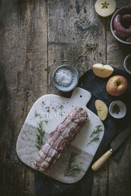 Свиная вырезка на столе со специями и ингредиентами — стоковое фото
