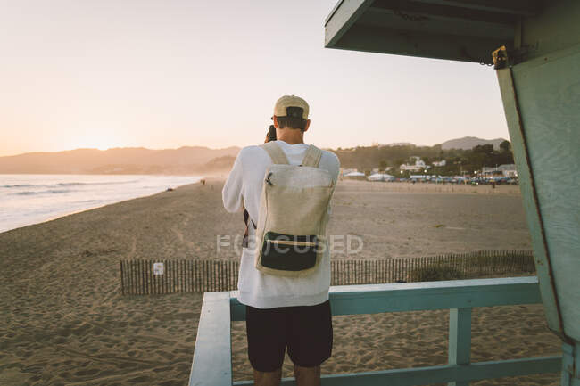 Uomo con macchina fotografica in piedi sulla spiaggia — Foto stock