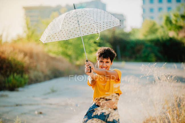 Joyeuse jeune femme tenant parapluie à l'extérieur par temps ensoleillé — Photo de stock