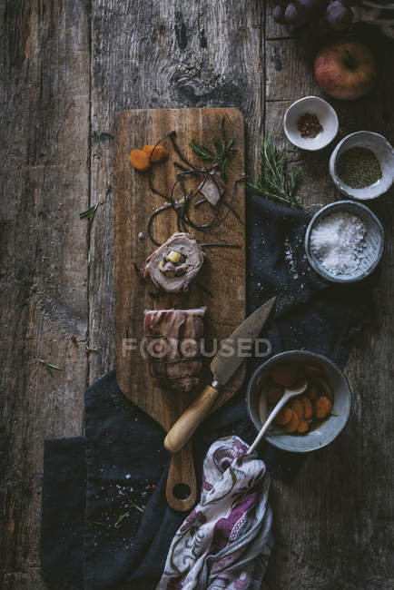 Sharp knife and assorted spices with delectable homemade sausage on wooden tabletop — Stock Photo
