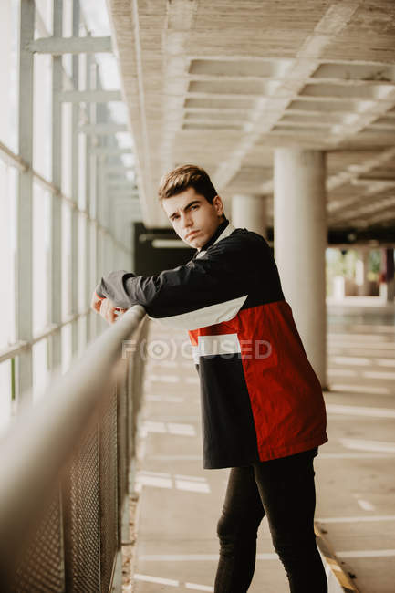 Young thoughtful man standing inside building and leaning on railing — Stock Photo
