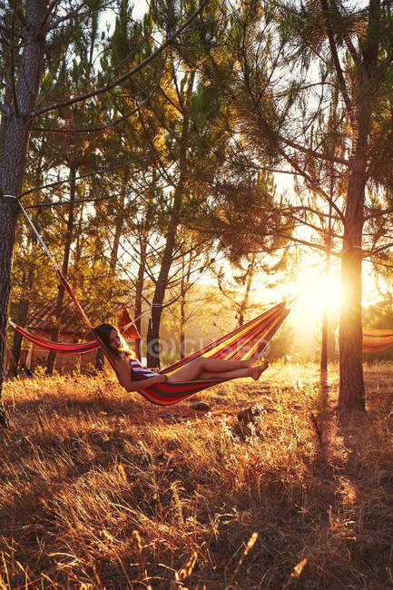 Woman lying in hammock at sunny woods — Stock Photo