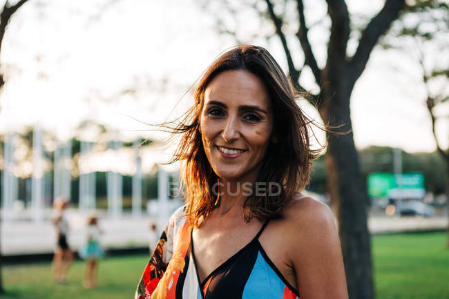 Portrait of smiling brunette woman in urban park — Stock Photo