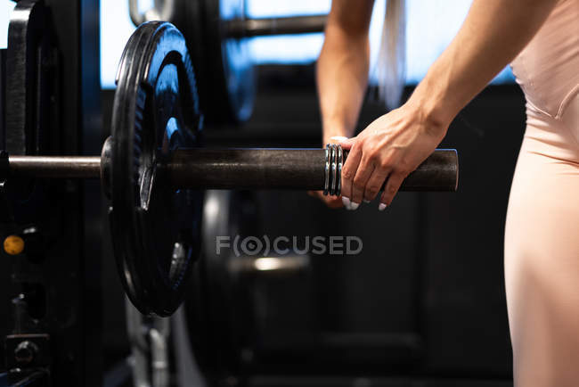 Close-up of female hands preparing barbell for workout in gym — Stock Photo